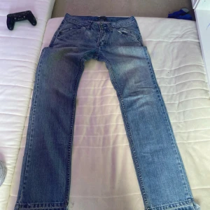 Blå jeans från Rabiez med råa kanter - Säljer ett par blå jeans från Rabiez by Ztyle Industry med coola råa kanter nertill och snygga detaljer vid fickorna. Jeansen har klassisk femficksdesign, normal passform och är tillverkade i denim. Perfekta för dig som gillar en avslappnad och trendig look.