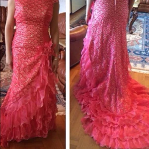 Rosa långklänning med volanger - Säljer en superfin rosa långklänning med glittriga detaljer och volanger nertill. Klänningen har ett mönster med guldinslag och en snygg blomdetalj i midjan. Perfekt för dig som vill sticka ut med en färgstark och elegant look.