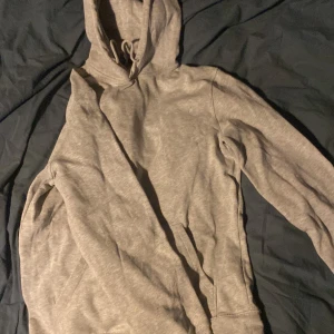 Grå hoodie med huva och fickor - En enkel och stilren grå hoodie med huva och snörning. Perfekt för chill dagar eller när du vill ha något bekvämt och avslappnat.