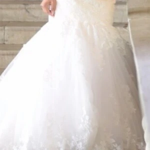 Vit lång brudklänning med spets - Maggie Sottero - Drömmig vit långklänning med vacker spets och glittriga detaljer. Klänningen har en markerad midja med ett dekorerat bälte och en vid kjol som ger en riktigt elegant siluett. Perfekt för dig som vill känna dig som en prinsessa.