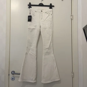 Offwhite bootcut jeans Dr Denim XS - Snygga offwhite jeans från Dr Denim, modell Macy Petite. Byxorna har bootcut-ben och klassisk femficksdesign. Tillverkade i ett mjukt bomullsmaterial med dragkedja och knapp framtill. Perfekta för dig som gillar en trendig och stilren look.