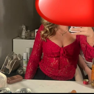 Röd spetsblus med knyt framtill - Säljer denna supersnu röda långärmade blusen från Nelly i genombruten spets med v-ringning och knyt framtill. Den är endast använd en gång, säljer då den inte kommer till användning💕