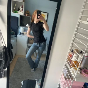 Svart spetsblus från Pieces - Snygg svart blus från Pieces med vackra spetsdetaljer. Perfekt för en elegant look. Blusen har korta ärmar och en rund halsringning.