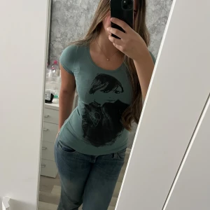 Grön t-shirt med tryck - Cool grön t-shirt från Cheap Monday med svart tryck av en person på framsidan och grafiskt motiv på ryggen. T-shirten är figurnära med rund hals och korta ärmar. Perfekt för dig som gillar streetstyle och unika prints. Vid frågor hör av dig! 