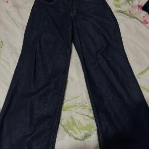 Mörkblå jeans från 157 wide fit - Mörkblå jeans från 157 med klassisk femficksdesign och kontrastsömmar. Modellen har breda ben och normal midja, vilket ger en avslappnad och trendig look. Perfekta för dig som gillar en loose och wide fit. Materialet är robust denim i bomull.