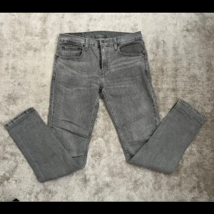 Levi's 512 grå jeans W32 L34 - Snygga grå Levi's 512 jeans med klassisk femficksdesign och smal passform. Jeansen har en något tvättad look och är tillverkade i mjukt denimtyg. Perfekta för dig som gillar en stilren och modern vibe.