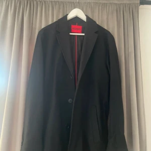 Svart rock från HUGO i ull och kashmir - Svart rock från Hugo boss. Storlek M/48 perfekt skick endast använd 1 gång. Äkta cashmere. Köpt för 4999