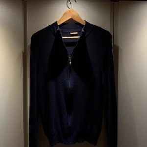 Stenströms - Mörkblå stickad full zip-tröja  - Mörkblå stickad tröja från Stenströms med full zip-dragkedja och ribbad krage. Tröjan har lång ärm och är tillverkad i ett mjukt, strukturerat material som passar perfekt för kyligare dagar. Enkel och stilren design som funkar till det mesta. Storlek M men sitter som S.