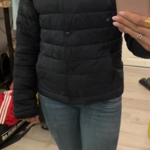 Svart pufferjacka från H&M, stl 164 - Säljer en svart pufferjacka från H&M i storlek 164. Jackan är quiltad med knappar framtill och har en klassisk, enkel design. Perfekt för kyligare dagar och lätt att matcha med olika outfits. Använd några gånger, passar en i xs/s😁