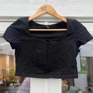 Svart croppad topp med kort ärm - En svart croppad topp med rundad urringning och korta ärmar. Enkel och stilren design som passar till många olika outfits. Tillverkad i mjukt material för en bekväm känsla.