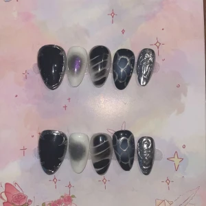 M - Svarta och silvriga press-on naglar - Snygga press-on naglar i svart, vitt och silver med coola mönster som swirl, skimmer och metallic. Setet innehåller 10 naglar i olika storlekar med både matta och glansiga ytor, samt detaljer i lila och krom. Perfekt för dig som vill sticka ut med unika naglar.