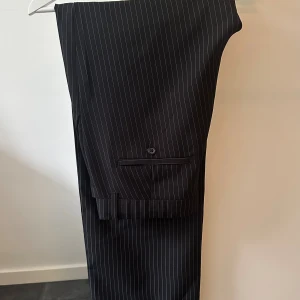 Randiga kostymbyxor Jack & Jones - Snygga svarta kostymbyxor från Jack & Jones med tunna vita ränder. Använt max 5 gånger och har inga synliga tecken på användning