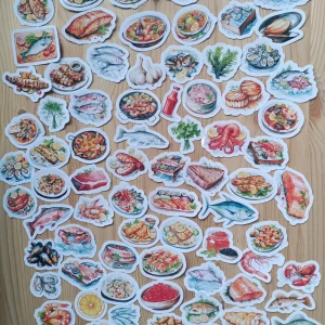 Seafood Stickers höjd 3.8cm - En färgstark samling av 80 st.  klistermärken 3.8cm i höjden med motiv av fisk, skaldjur, sushi och läckra maträtter från havet. Perfekt för att dekorera laptops, mobilskal eller anteckningsböcker och visa din kärlek till mat och havsinspirerad stil. Passar dig som gillar kreativitet och matglädje!