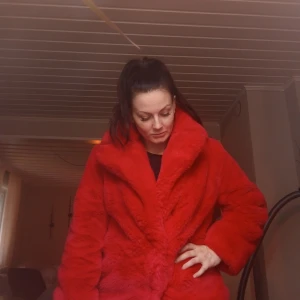 Röd fluffig pälsjacka med krage - Säljer en riktigt snygg röd pälsjacka med bred krage och lång ärm. Jackan är supermjuk och har en oversized passform som ger en cool vibe. Perfekt för dig som vill sticka ut och hålla dig varm. Jackan är helröd och har en lyxig, fluffig känsla. Jackan är i väldigt fint skick, enda effekten är att en av knapparna saknas, men inget som stört mig vid användning.  Storlek 34, men jag som är en 36 har den passat ändå. 