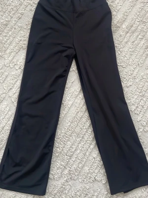 Svarta vida byxor i stretchigt material - Säljer ett par svarta byxor med breda ben och hög midja. Byxorna är gjorda i ett stretchigt och mjukt material som ger en skön passform. Perfekta för dig som gillar en enkel men trendig look.