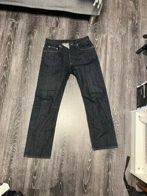 Mörkblå selvedge jeans från Sandro Paris - Säljer ett par mörkblå selvedge jeans från Sandro Paris i regular fit. Klassisk femficksmodell med raka ben och snygga kontrastsömmar. Jeansen är tillverkade i kraftigt denimtyg och har en clean look utan slitningar eller tvättar. Nästintill helt oanvända!