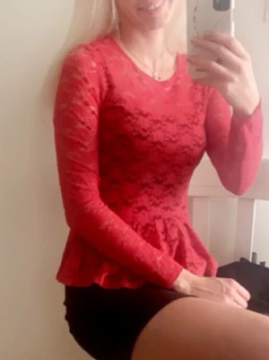 Röd spetsblus med volang - Säljer en röd långärmad blus i spets med volang nertill. Blusen har rund halsringning och dragkedja i ryggen. Tunn och genomskinlig spets ger en snygg look, perfekt att styla med jeans eller kjol. Det är storlekek 38 men skulle säga att den är söm 34/36 