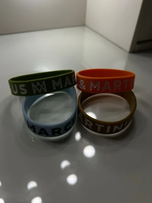 Marcus & Martinus armband - Säljer fyra färgglada Marcus & Martinus armband i silikon. Färgerna är grön, orange, ljusblå och brun, alla med vit eller svart text. Dessa går ej att köpa längre, och är köpta på mmstore i nyskick!! 🤍