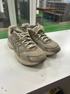 Beige ASICS GEL-1130 sneakers - Säljer ett par ASICS GEL-1130 sneakers i beige och grå toner. Skorna har meshpaneler för bra ventilation, detaljer i mocka och klassisk ASICS-logga på sidan. De har snörning och en chunky sula som ger retrovibbar. Perfekta för dig som gillar dadcore-stilen.