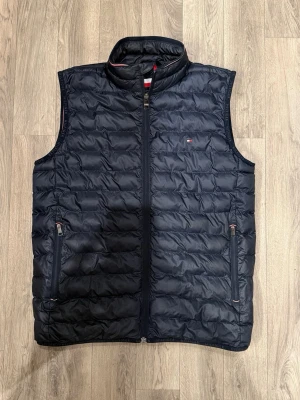 Tommy Hilfiger Quilted Down Vest – Svart – Strl S - Sjukt snygg svart Tommy Hilfiger dunväst i mycket fint skick i storlek S. Mått - Axelbredd: 41cm, Bröstvidd: 37,5cm, Längd: 65,5cm, Midja: 48,5cm. Hör av dig vid funderingar!🤝