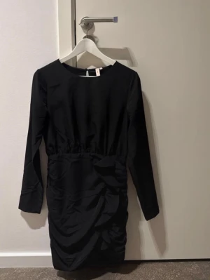 Svart klänning  - Säljer denna svarta klänning från Nelly! Använd en gång så är i jättebra skick⭐️ Volanger och lite öppen i ryggen