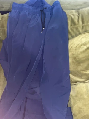 Nike Unlimited blå tracksuit - Nike Unlimited träningsbyxor i mörkblå färg med tapered passform och elastisk midja med snörning. Tillverkade i lätt polyester med Dri-FIT-teknologi för att hålla dig torr. Snygg, sportig look med diskret Nike-logga på benet.