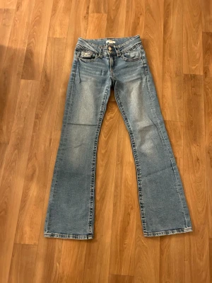 Blå bootcut jeans Gina Tricot 158 - Snygga ljusblå bootcut jeans från Gina Tricot i storlek 158. Två knappar där fram och är lågmidjade. Inget som uppmärksammar användning!