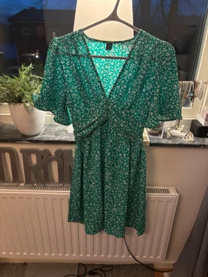 Grön klänning med vita blommor  - Grön klänning med vita blommor, exakt skick är svårt att säga då alla har olika åsikter men enligt mig är skicket bra och jag kan inte hitta några skador när jag kolla igenom