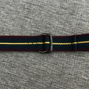 Randigt tygbälte från Polo Ralph Lauren - Snyggt tygbälte från Polo Ralph Lauren med marinblå, vinröda och gula ränder. Bältet har en metallspänne med Polo-logga och är tillverkat i slitstarkt material. Perfekt accessoar för att lyfta din outfit.