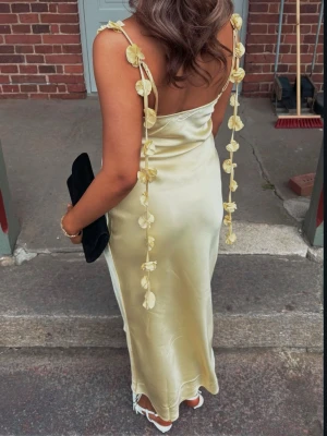 Balklänning  - Superfin långklänning i ljusgul satin-look med smala axelband dekorerade med små blommor. 🥰