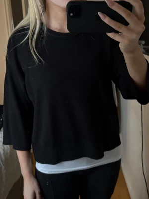 Svart loose tröja med trekvartsärm - En svart tröja med loose passform och trekvartsärm. Tröjan har en enkel rund halsringning och är gjord i ett mjukt bomullsliknande material. Perfekt till chill dagar eller när du vill ha en clean och enkel look.