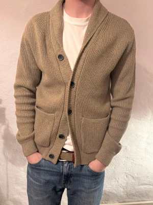 Stickad Cardigan - Säljer en beige stickad cardigan från Petrol Industies.  med grov ribbstickning och fyra stora knappar framtill. Koftan har två rejäla fickor och en bred krage som ger en chill och avslappnad look. Perfekt för lager på lager under kyliga dagar.  nypris 999kr säljes för 199kr. Storlek S