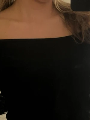Svart offshoulder topp - Säljer en svart offshoulder topp i storlek M. Toppen har en stilren, axelbandslös design och är figurnära. 
