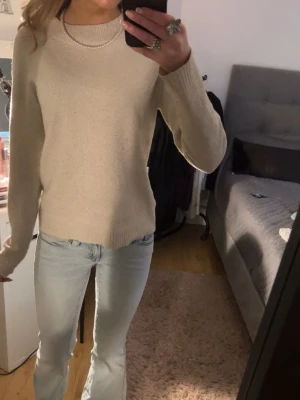 Beige stickad tröja med rund hals - Säljer en enkel och stilren beige stickad tröja med rund halsringning. Tröjan har lång ärm och en mjuk, bekväm passform som passar perfekt till jeans. Perfekt basplagg för garderoben!