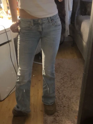 Ljusblå bootcut jeans - Säljer ett par ljusblå jeans med bootcut-modell och låg midja. Jeansen har klassiska fickor fram och bak, samt snygga sömdetaljer. Perfekta för dig som gillar en avslappnad men ändå trendig look.