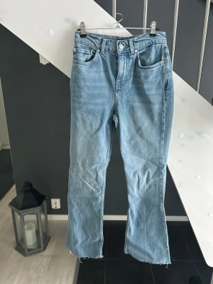 Ljusblå raka jeans med rå kant - Säljer ett par ljusblå jeans med rak passform och hög midja. Jeansen har klassisk femficksdesign och rå, fransig kant nertill för en avslappnad vibe. Perfekta till sneakers eller boots och funkar året runt. Materialet är klassisk denim i bomull.