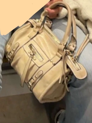 Beige handväska med detaljer - Säljer en baleciaga liknande beige handväska med coola spännen och dragkedja framtill. Perfekt storlek för att få plats med allt du behöver och passar till många olika outfits.💕💕