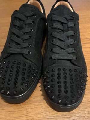 Svarta sneakers med nitar från Louboutin - Jag säljer ett par stilrena svarta Louboutin-skor i storlek 43. Nästan oanvända och har endast använts cirka 6 gånger. Enligt mig är detta en av de snyggaste modellerna från Louboutin - tidlös och lätt att matcha med nästan alla outfits tack vare svarta färgen. Loggan på insidan av skon är något suddad och syns knappt, men påverkar varken utseende eller användning. Skorna är mycket bekväma i passformen och redo att användas direkt. Inga defekter eller problem vad jag kan se. Tar gärna emot bud! 