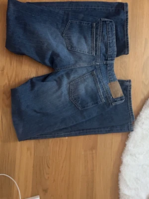 Blå bootcut jeans från Weekday - Säljer ett par klassiska blå jeans från Weekday med bootcut-modell. Jeansen har låg midja, fem fickor och snygga slitningar framtill. Materialet är robust denim i bomull och passformen är loose med utsvängda ben. Inga tecken på användning och jag är 167 så skulle säga att de är strl 34/36