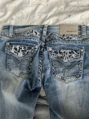 Vintage grace in La bootcut jeans - Säljer ett par ikoniska Grace in LA jeans – äkta vintage med de eftertraktade broderade & paljettdekorerade bakfickorna. Perfekta för dig som älskar Y2K, cowgirl core, festival vibes eller statement-denim. Skriv gärna för fler bilder och mått.