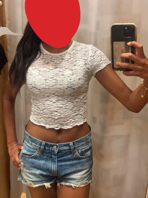 Vit spets croppad topp - Säljer en vit croppad topp med spets mönster från Spanien . Perfekt till sommaren och enkel att styla med jeans eller kjol.