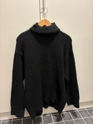 Svart stickad polotröja - Svart polotröja med bred, ribbad krage och långärmad design.