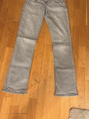 Gråa bootcut jeans - Säljer ett par gråa jeans med bootcut passform. Byxorna har klassisk femficksdesign och raka ben som blir lite vidare nedtill. Materialet är mjukt och skönt, perfekt för dig som gillar en avslappnad stil. Passar till det mesta och är riktigt snygga till sneakers.