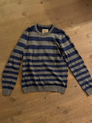 Randig blå och grå tröja från Esprit - Säljer en slim fit tröja från Esprit i storlek S. Tröjan har breda horisontella ränder i marinblått och grått, rund halsringning och ribbade muddar. Perfekt för dig som gillar klassisk stil med en modern twist.