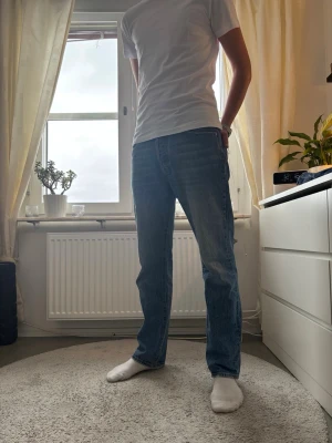 Blå raka jeans  - Säljer ett par klassiska blå jeans från Levi's med rak passform och normal midja. Jeansen har en tidlös look med lätt tvättad effekt och är tillverkade i slitstarkt denim. Perfekta för dig som gillar enkel och clean stil.