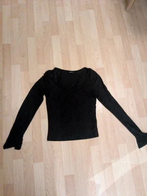 Svart långärmad topp från Gina Tricot soft touch stl. M - En svart långärmad topp från Gina Tricot med lätt utsvängda ärmslut och u-ringad hals. Toppens material är mjukt och stretchigt.
