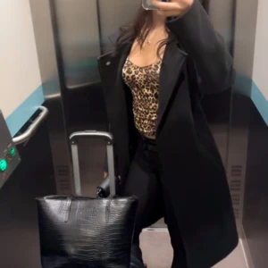 Svart rock med klassisk krage - Snygg svart rock med klassisk krage och rak passform. Jackan är lång och har en stilren design som passar perfekt till både jeans och klänning. Materialet ser ut att vara ull eller en ullblandning, vilket gör den extra varm under kyliga dagar.