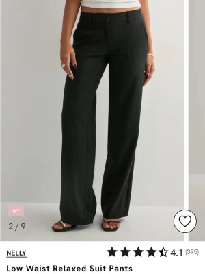 Svarta kostymbyxor från Nelly - Snygga svarta kostymbyxor från Nelly med låg midja och breda, raka ben. Byxorna har hällor för bälte och klassisk kostymlook. Perfekta för dig som gillar en relaxed och trendig stil.