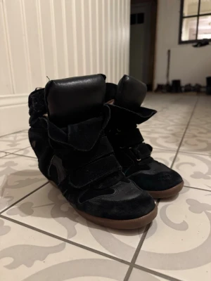 Svarta Isabel Marants - Säljer ett par äkta svarta Isabel Marants i storlek 37, väl använda men fyller fortfarande sin funktion. Ett hål fram i tån men som bara är i första lagret av mockat samt att läder delen av ena innersulan har lossnat (se bilder)