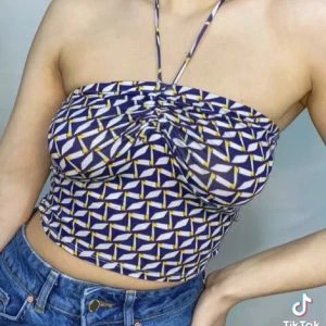 Mönstrad halterneck tubtopp från Bear Dance - Säljer en snygg tubtopp från Bear Dance med halterneck och coolt geometriskt mönster i blått, vitt och gult. Toppen har rynkdetalj framtill och är croppad. Perfekt för dig som gillar färg och mönster. Materialet är mjukt.  Väldigt stretchig.  Den har sån här gummi plats över brösten så den inte åker ner. Storlek L